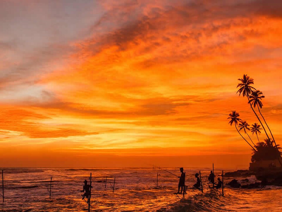 Lever de soleil doré sur la côte du Sri Lanka avec des silhouettes de bateaux de pêche